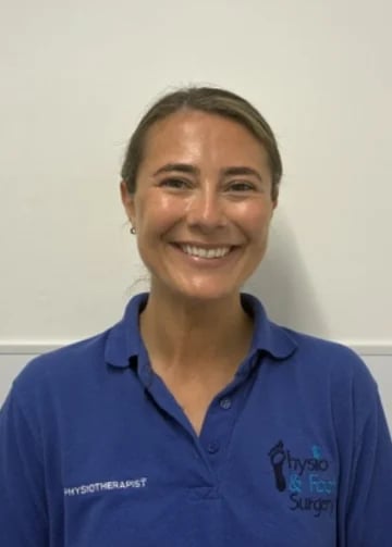 Portrait of a smiling woman wearing a blue physiotherapy polo shirt against a white background